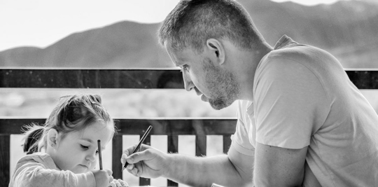 A father and daughter sitting by the water coloring.