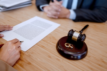 person signing divorce papers with a lawyer