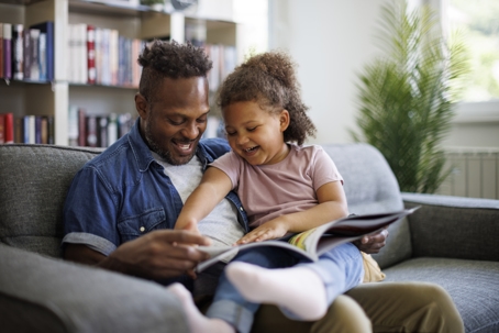 father and daughter on the couch reading a book