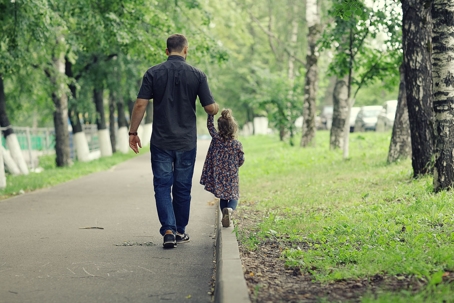A father and daughter walking on a trail together.