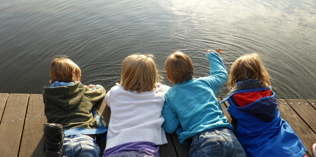 children laying on dock overlooking water