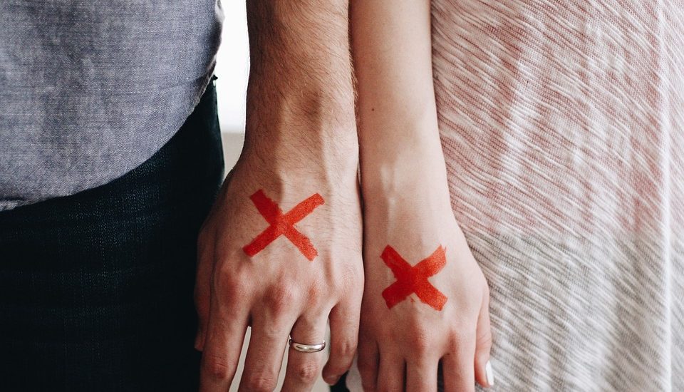 man and woman side by side with X on hands