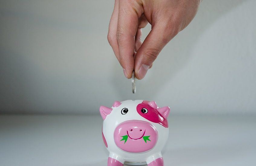 adding coin to pink piggy bank