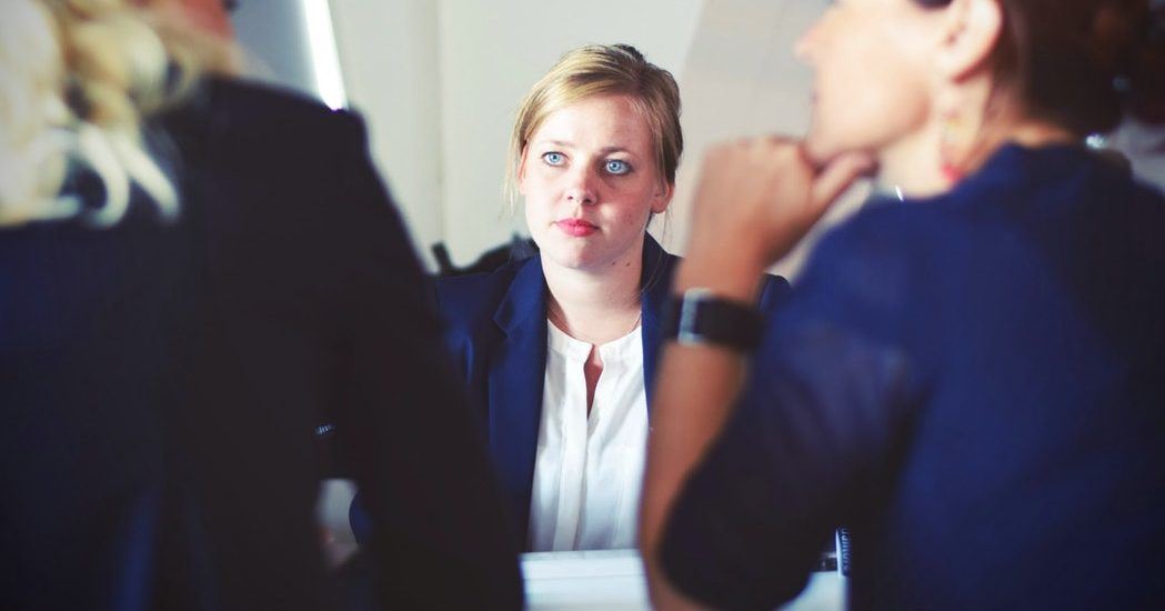 three woman in suits in the middle of a meeting